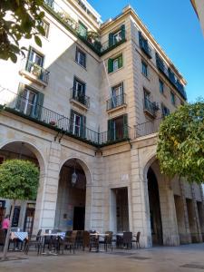 un bâtiment avec des tables et des chaises devant lui dans l'établissement Old Center Inn Alicante, à Alicante