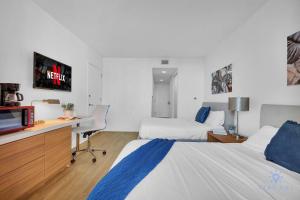 Una habitación de hotel con dos camas y un escritorio con televisión. en Spectacular Studio Amazing Amenities Bay View, en Hallandale Beach