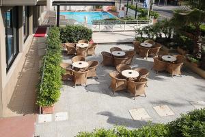 an outdoor patio with tables and chairs and a pool at Hotel Du Soleil in Rimini