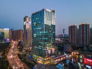un alto edificio di vetro in una città di notte di Echarm Hotel Nanning East Railway Station a Tunli
