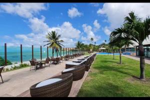 a row of tables and chairs next to the ocean at Tabatinga Flat - Pé na Areia! Beira Mar! in Conde