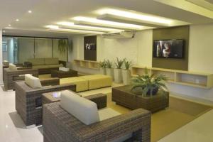 a living room with wicker furniture and a tv at Tabatinga Flat - Pé na Areia! Beira Mar! in Conde