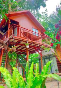 a red house with a balcony in the trees at Huy Hoàng Homestay Kiên Giang in Lai Sơn