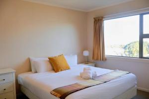 Un dormitorio con una cama blanca con una ventana grande. en Walk to Town center with Views, en Queenstown