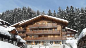 un gran edificio en la nieve con árboles en Apartment Brunnen - GRIWA RENT AG, en Grindelwald