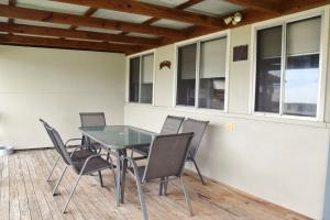 a dining room with a glass table and chairs at Sunshine Cottage - Bring your own linen. in South West Rocks