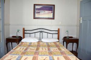 a bedroom with a bed with two nightstands and two lamps at Sunshine Cottage - Bring your own linen. in South West Rocks