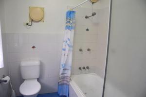 a bathroom with a toilet and a tub and a shower at Sunshine Cottage - Bring your own linen. in South West Rocks +13 photos
