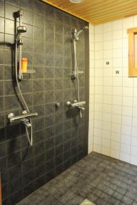 y baño con ducha y azulejos negros. en Loma-Väkkärä Holiday Cabins Saimaa, en Liiansaari