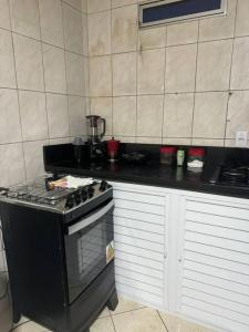 a kitchen with a black stove and white cabinets at Excelente apartamento no centro in Macaé