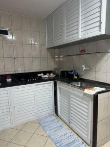 a kitchen with white cabinets and a counter top at Excelente apartamento no centro in Macaé +2 photos