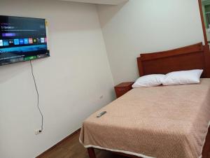 a bedroom with a bed with a flat screen tv on the wall at La campiña in Lima