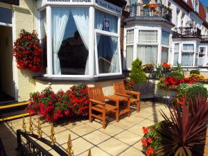 a patio with two chairs and flowers in front of a building at Maluth Lodge in Great Yarmouth