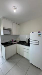 a kitchen with white cabinets and a white refrigerator at Maragogi Peroba Ville Residence in Maragogi