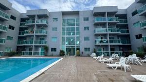 a large apartment building with a swimming pool and chairs at Maragogi Peroba Ville Residence in Maragogi