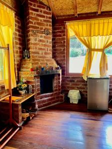 a living room with a brick fireplace and yellow curtains at Munay Wasi by Hospedaje Puntzán in Baños