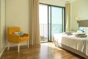 ein Schlafzimmer mit einem Bett und einem Stuhl und einem Fenster in der Unterkunft Villa Eden Sky in Prazeres in Prazeres + 33 Fotos