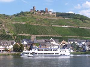 a white boat on the water with a castle in the background at Gasthaus Rebstock in Alken