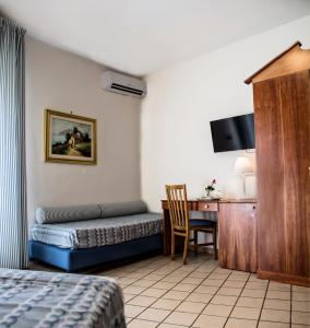 a bedroom with a bed and a desk with a chair at Hotel Sirenetta in Isola delle Femmine