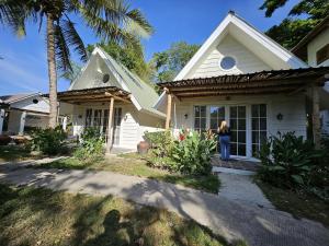 a woman standing on the porch of a house at Pasir Putih resort & Cafe in Maluk