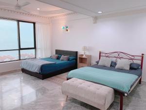 une chambre avec deux lits et un canapé et des fenêtres dans l'établissement Glory Beach Duplex Ocean View - 8Pax 3BR & FREE Disney Hotstar, à Port Dickson 30 autres photos