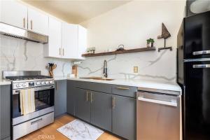 una cucina con mobili bianchi e un frigorifero nero di Ocean View Studio Near Convention Center and Beach a Long Beach