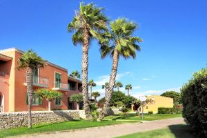 two palm trees in front of a building at iGV Club Baia Samuele in Sampieri