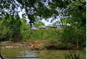a view of a river with houses in the background at Wild Elephas in Udawalawe