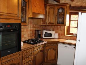 a kitchen with wooden cabinets and a stove and microwave at Maison périgourdine avec cheminée, animaux acceptés, proche Dordogne - FR-1-616-416 in Naussannes