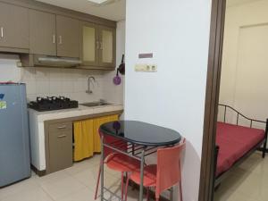 cocina pequeña con mesa y cama en Apartemen Bogor Valley Family Staycation, en Bogor