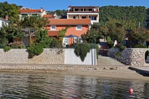 a retaining wall next to a body of water with houses at Seaside house for families with children Barbat, Rab - 22294 in Rab