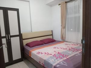 Un dormitorio con una cama con almohadas rojas y una ventana. en Apartemen Bogor Valley Family Staycation, en Bogor 4 fotos más