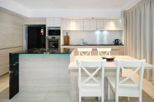Una cocina con una encimera con taburetes blancos y una mesa. en Saffire Seaside Serenity, en Mooloolaba