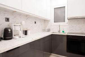 a white kitchen with a sink and a coffee maker at Afroditi in Athens +7 photos
