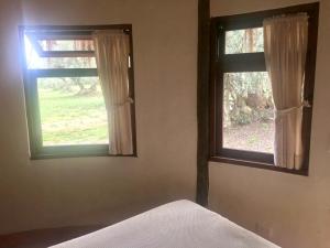 a bedroom with two windows and a bed in it at Habitación Ancestral Sol Muisca in Villa de Leyva