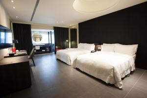 a hotel room with two beds and a desk at Hotel Lainn in Kaohsiung