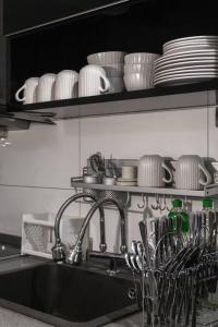 um lavatório de cozinha com pratos e pratos numa prateleira em Georgetown Karpal Singh Getaway 4BR 娱乐设施洋房乔治市 em Jelutong