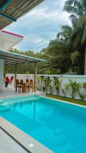a blue swimming pool on a patio with a table and chairs at Pinky Bungalow Resort & Villa - SHA Extra Plus in Ko Lanta
