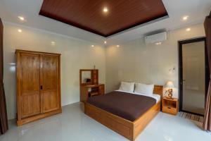 a bedroom with a bed and a wooden cabinet at The MAJE Private Villa in Ubud