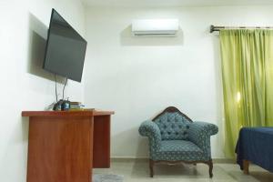a living room with a chair and a television at Gran Ubicación Terraza Privada Jacuzzi in Cozumel