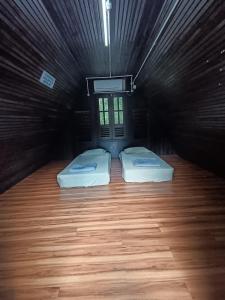 two beds in a dark room with wooden floors at Kuala Woh Resort in Tapah