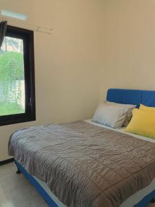 a bedroom with a bed with a blue headboard and a window at Batu Uma Villa in Tlekung