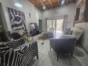 a living room with a zebra print couch and chairs at Kruger Amani Bush Retreat in Marloth Park