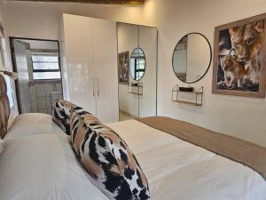 a bedroom with a bed with cow pillows and mirrors at Kruger Amani Bush Retreat in Marloth Park +42 photos