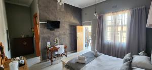a bedroom with a bed and a desk and a television at Bo Kamer Guesthouse in Ermelo