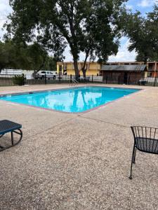 a swimming pool with a chair and a bench at Hotel Isabella in Uvalde