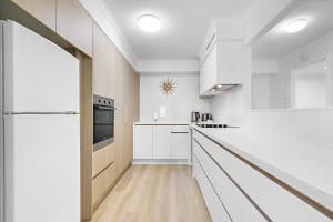 a kitchen with white cabinets and a refrigerator at Serenity Apartments Noosa in Noosa Heads