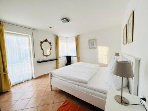 a white bedroom with a bed and a lamp at Ferienwohnungen Birkenhof in Bad Wörishofen