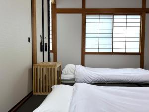 two beds in a room with a window at Hook House Stay Kanazawa in Kanazawa