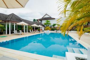 a pool at a resort with chairs and umbrellas at The Sands 2 bedroom apartment Naiharn in Nai Harn Beach